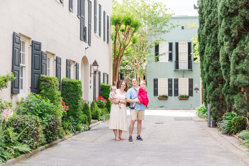 mom and dad holding toddler girls in historical Charleston by Bruna Firkins Photography