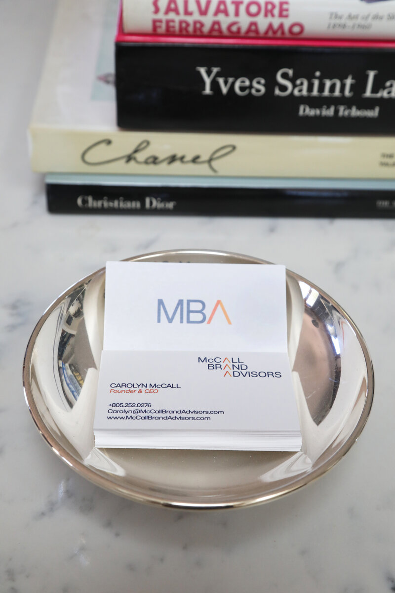 McCall Brand Advisors business cards in a silver bowl next to fashion books