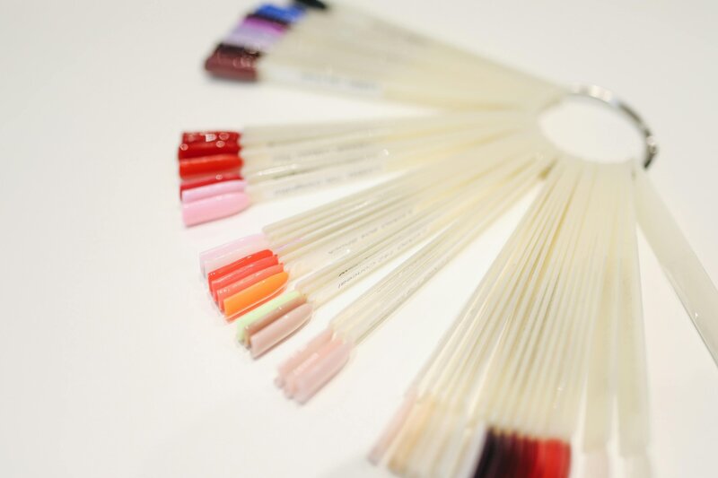 Fan of gel polish swatches arranged in a color gradient at Maven + Grace Salon, used to customize nail services with precision and style.