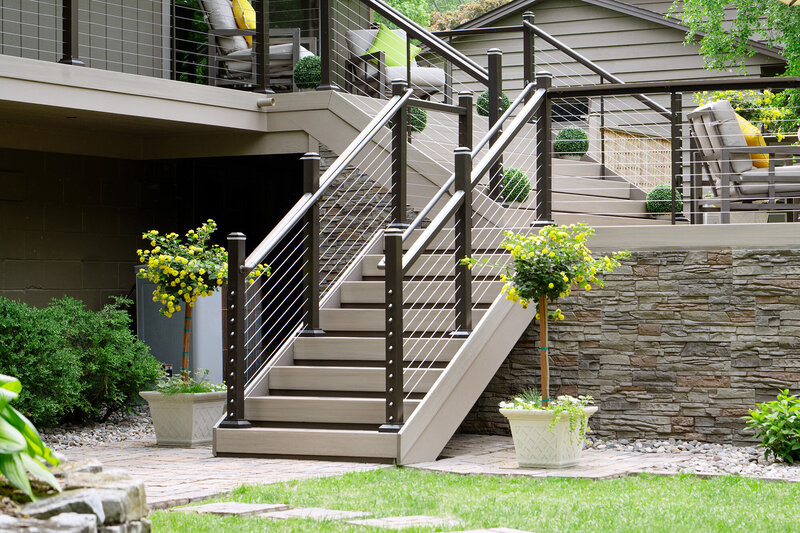 Deck staircase with cable railing and post cap lights, and contrasting riser and tread colors. 