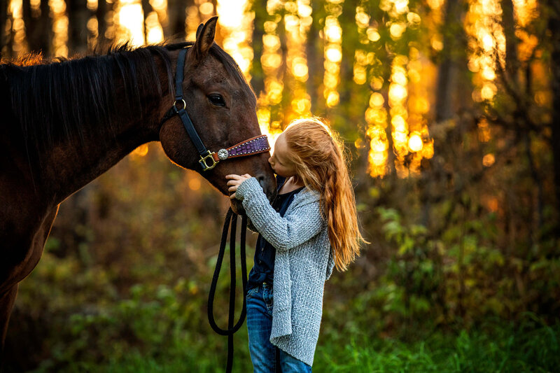 little girl with red hair kissing her horse