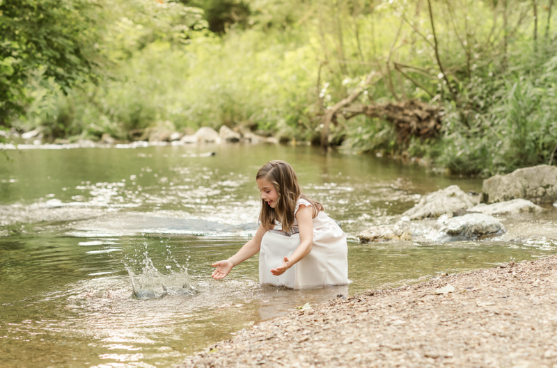 Young girl playing in a creek during an outdoor family photography session in Lancaster, Pennsylvania.