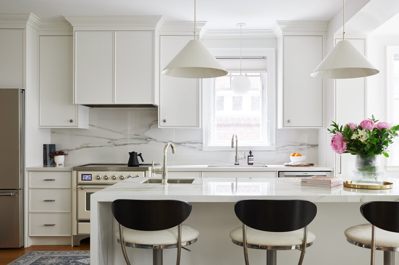 A bright and airy modernized kitchen space featuring a marble kitchen island and backsplash