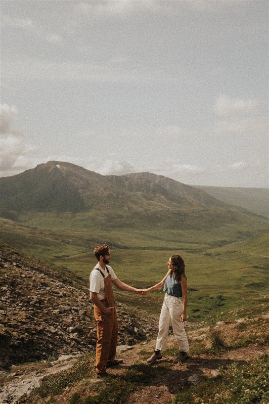 A couple holding hands on a mountain overlook.