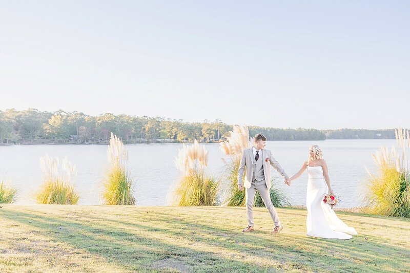 Bride and groom walking along the shore of Lake Martin | New Water Farms Wedding Photography