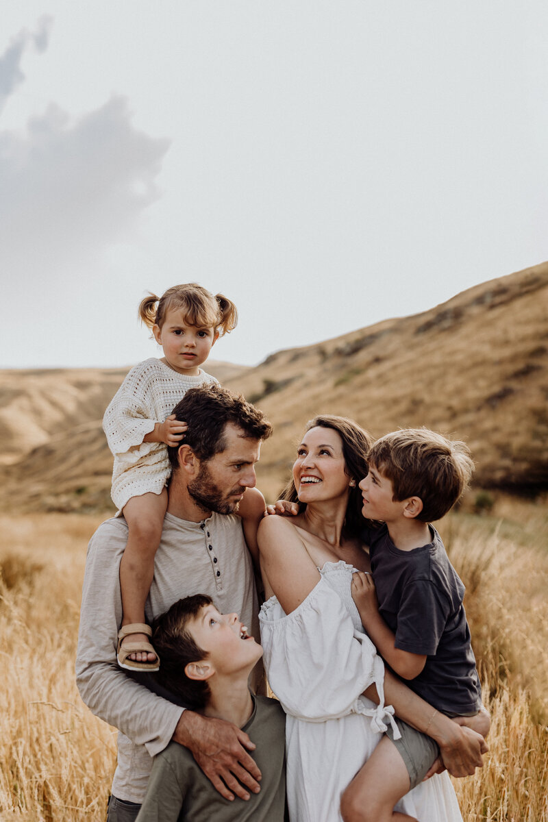 A family of five hugging and looking at one another while they're photographed by Christchurch photographer Lucy Jane Photography