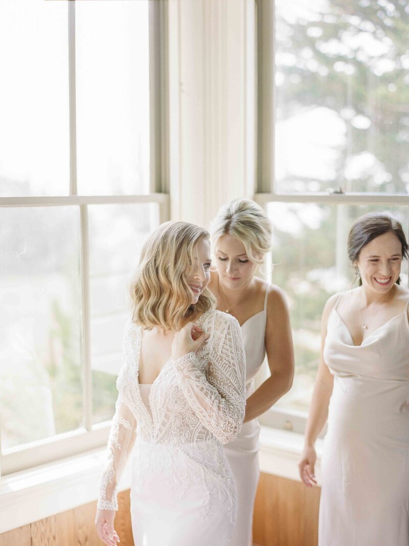bridesmaids helping bide with dress