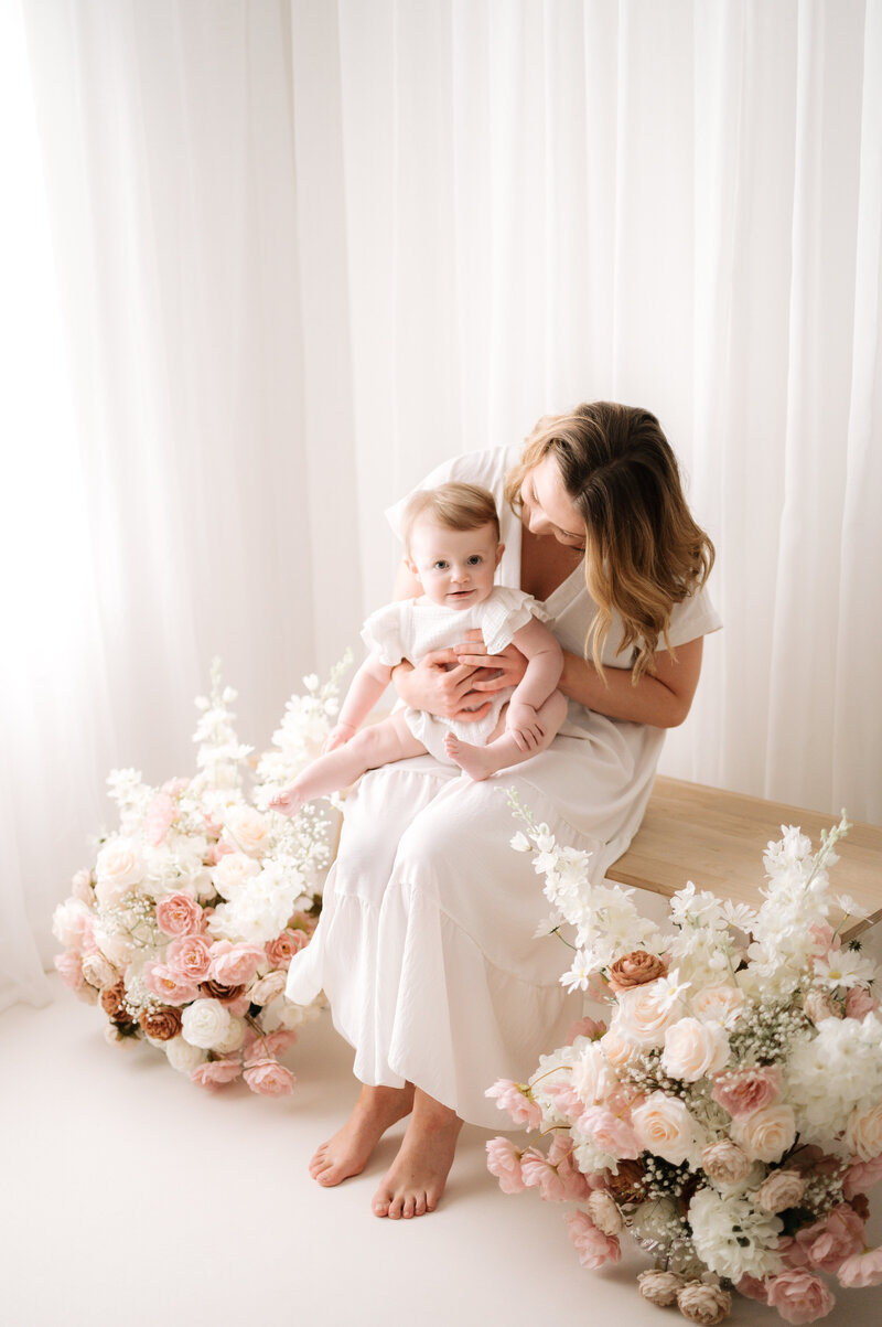 Little girl sitting on her mums lap smiling at Horsham family photoshoot