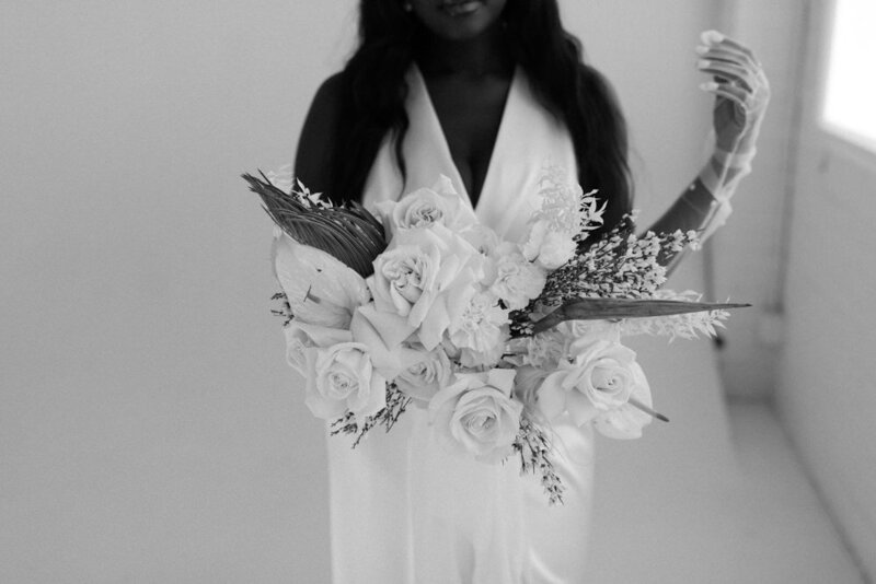 close up of bride in white studio holding flowers towards camera
