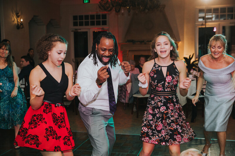 DJ Marz dancing joyfully with two young guests on a wedding dance floor, creating an energetic and inclusive party atmosphere.