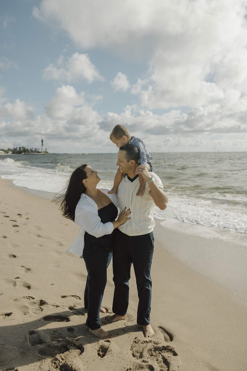 family plays with son on the beach in south florida