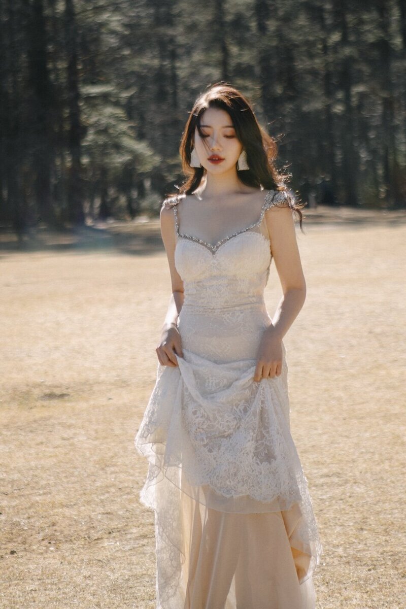 Bride in a couture dress shot in dramatic trees with mountains in the background.