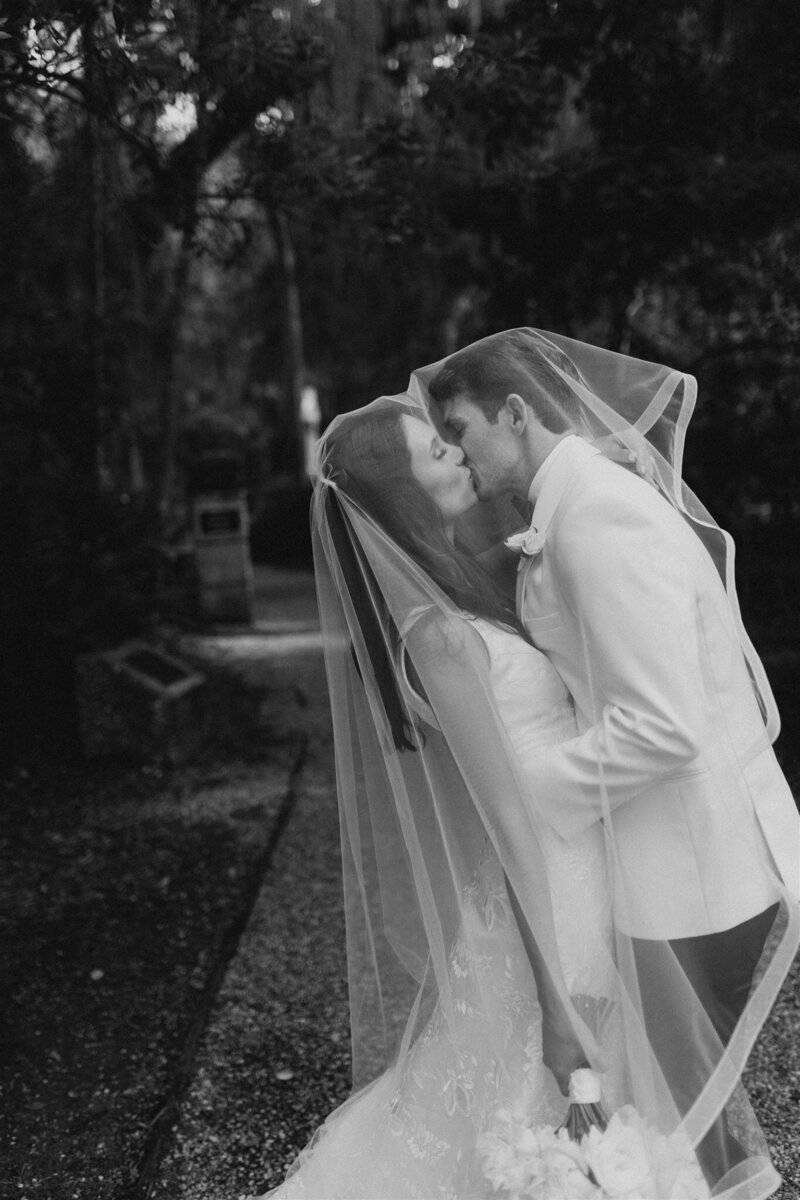 bride and groom kiss under veil