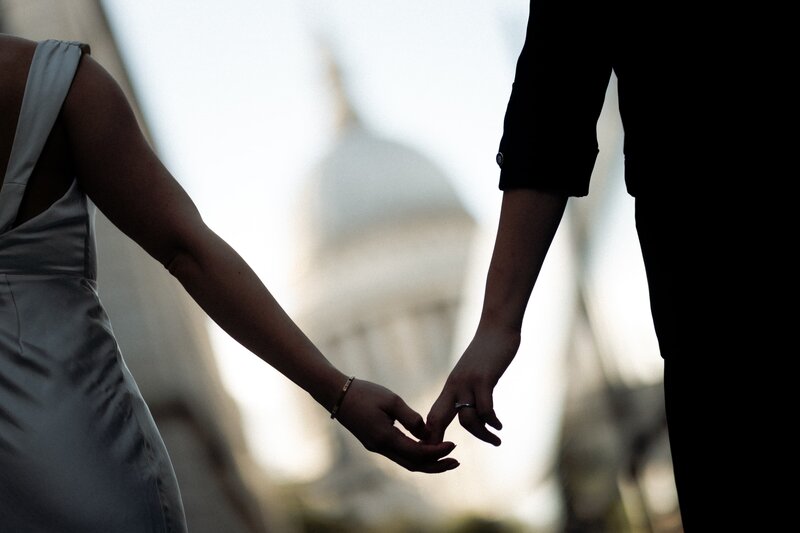 Bride and groom holding hands in front of St Paul's cathedral for wedding photography