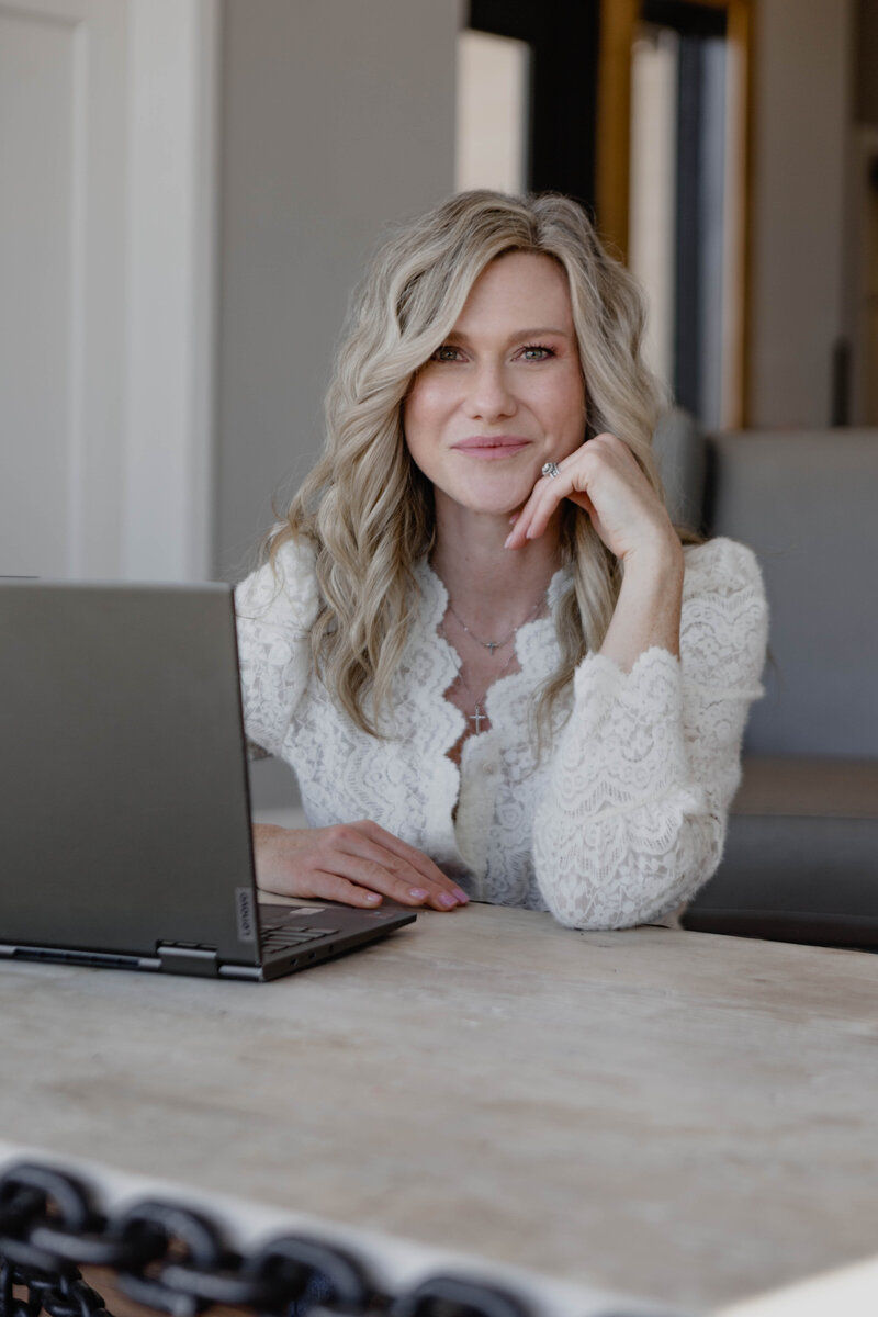 Kristin Tibbs smiling at her desk in black top, professional portrait
