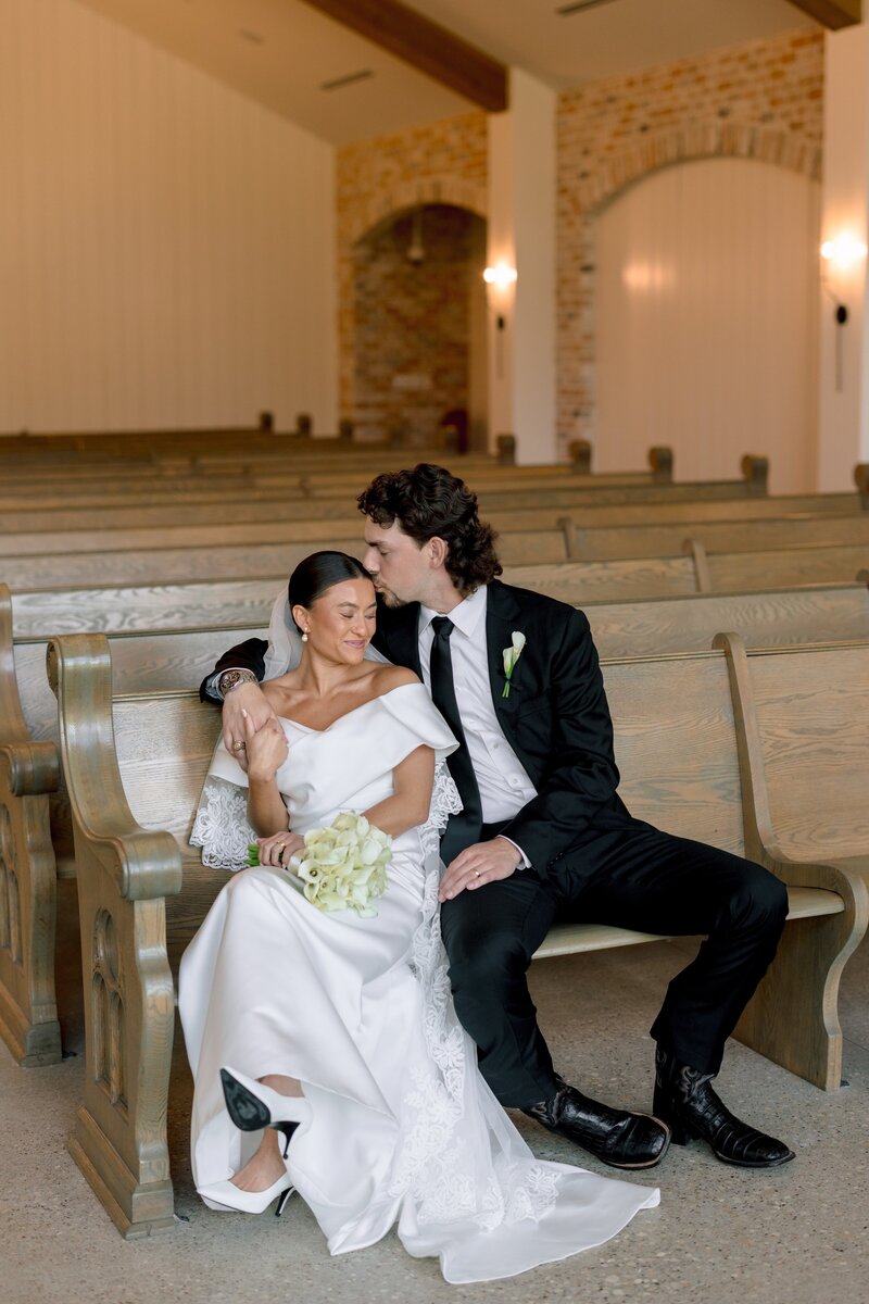 Portrait of a bride in an elegant lace dress leaning against a stair railing