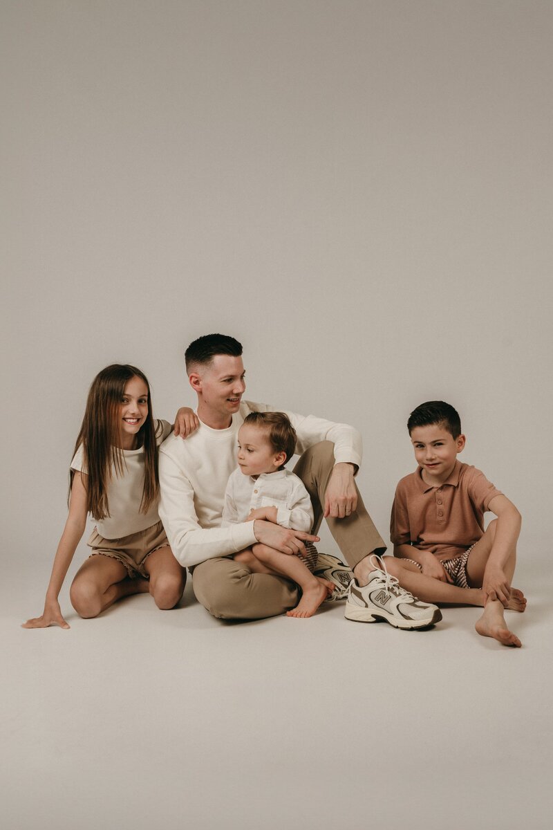 Papa met zijn 3 kinderen in een fotostudio