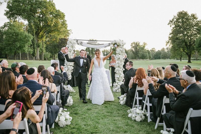 A wedding party cheers as the bride and groom kiss in the Bonnet Island Estate Chapel. A burnt sienna and tan color scheme