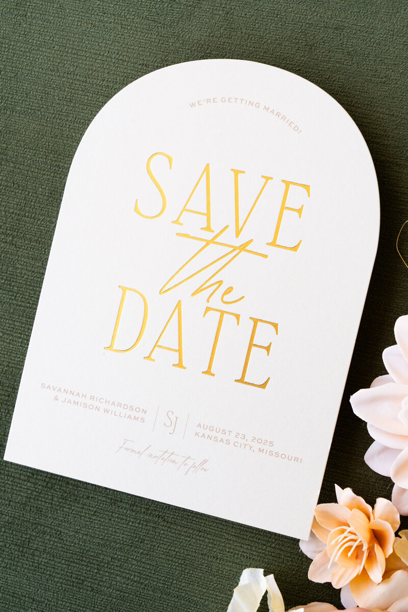 White curved menu card on a plate with a brown velvet napkin and flowers