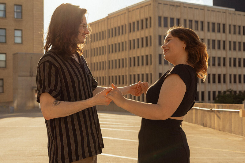 Couple holding hands in the sunset on a roof top in Winnipeg