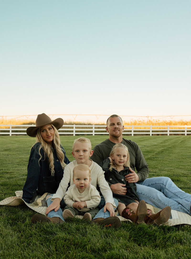 Candid family photo of a husband and wife building a mini snowman with their baby.