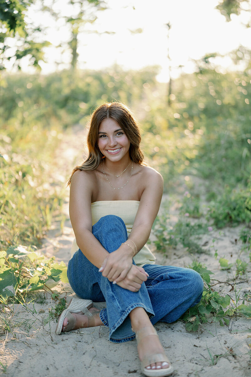 Senior sitting in the Lake Michigan dunes posing for her summer senior photos.
