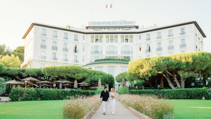 Classical Walking shot of the couple with palms in the garden of the Grand Hôtel du Cap Ferrat