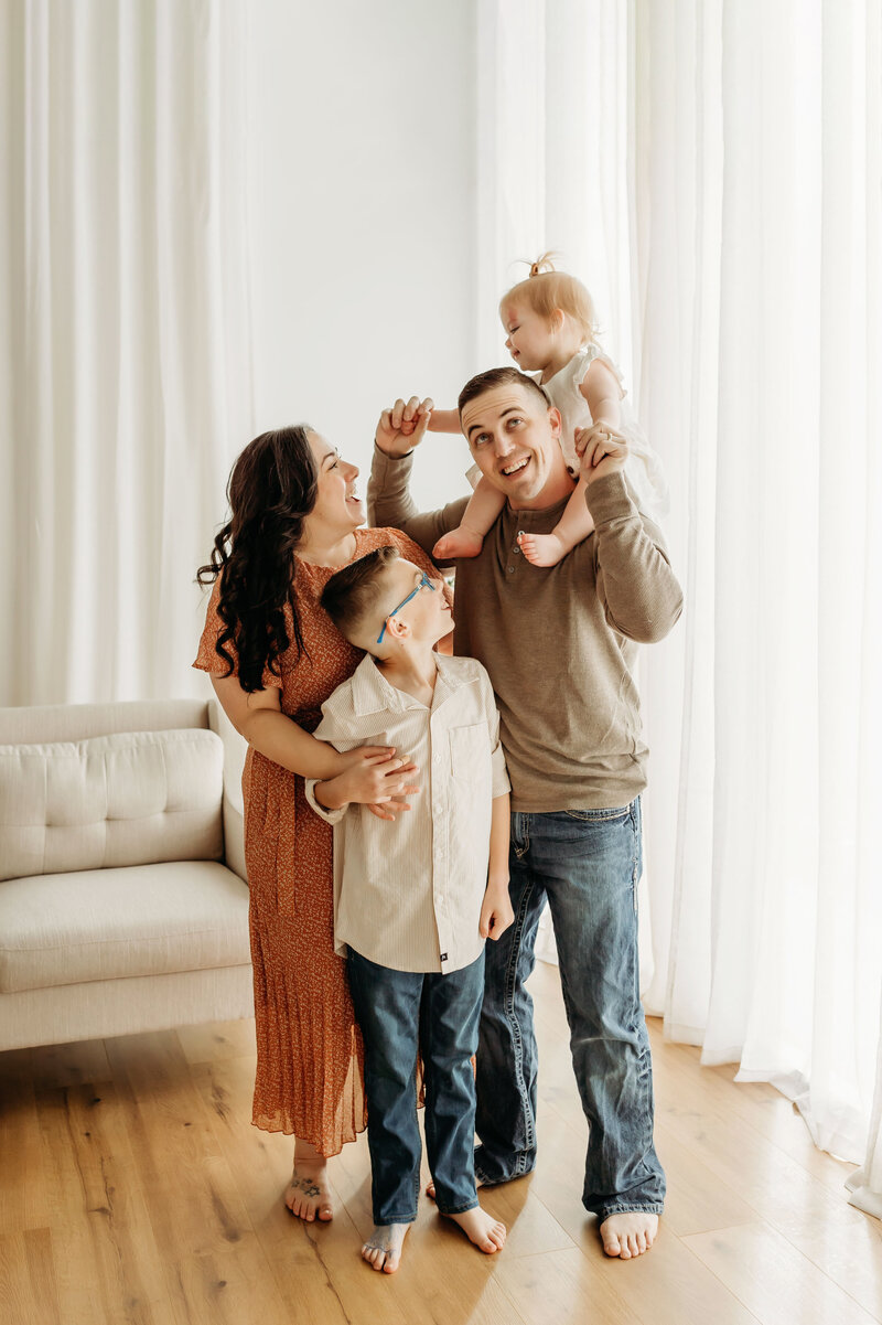 A family stands together smiling at each other inside a Vancouver Washington photography studio