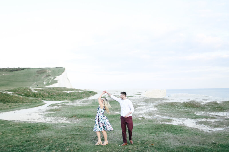couple-twirling-above-cliffs-during-engagement-shoot-in-berkshire-by-leslie-choucard-photography