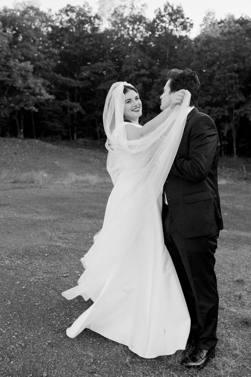 Hudson Valley wedding couple dance in the grass in front of the trees (black and white photo)