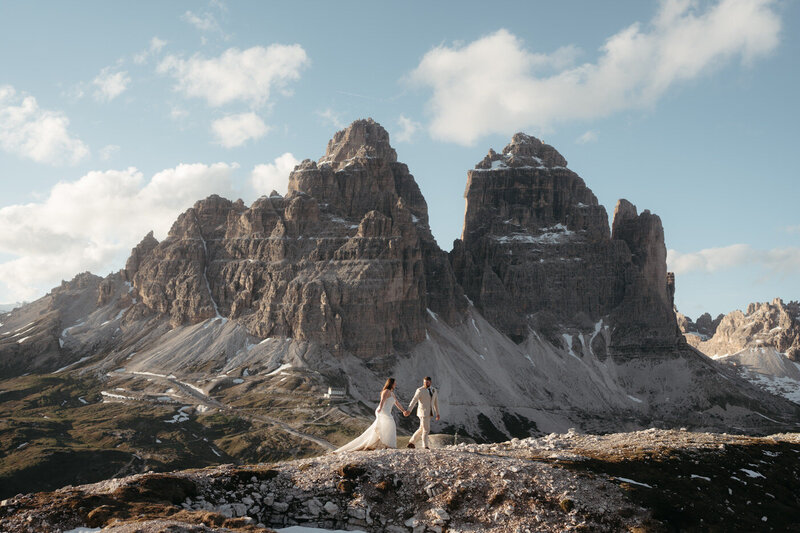 Dolomites Elopement | Couple walks along the a mountain ridge with Tre Cime behind them