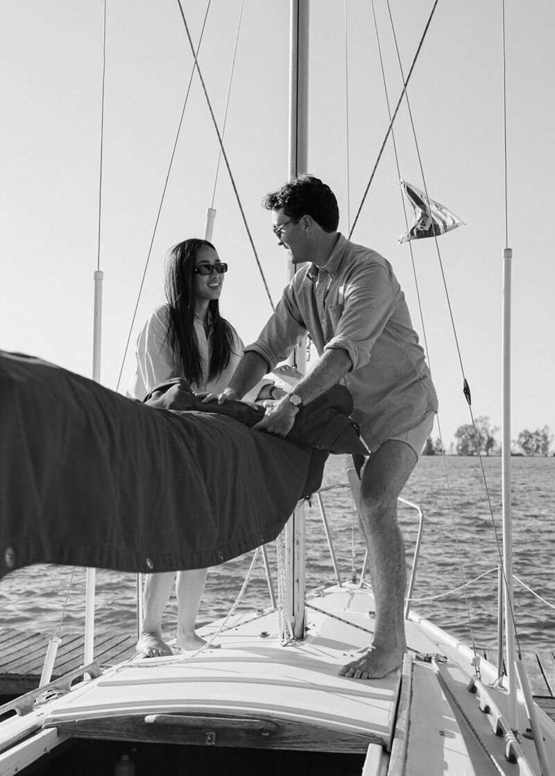 A black and white photo of a man and woman on a sailboat