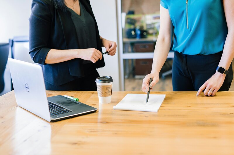 Two women at a desk with a laptop, engaged in professional supervision and case consultation in Littleton, Colorado.
