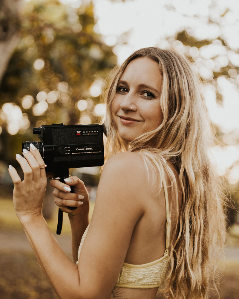 sunnie heers, photography coach, posing with her super 8 camera outside