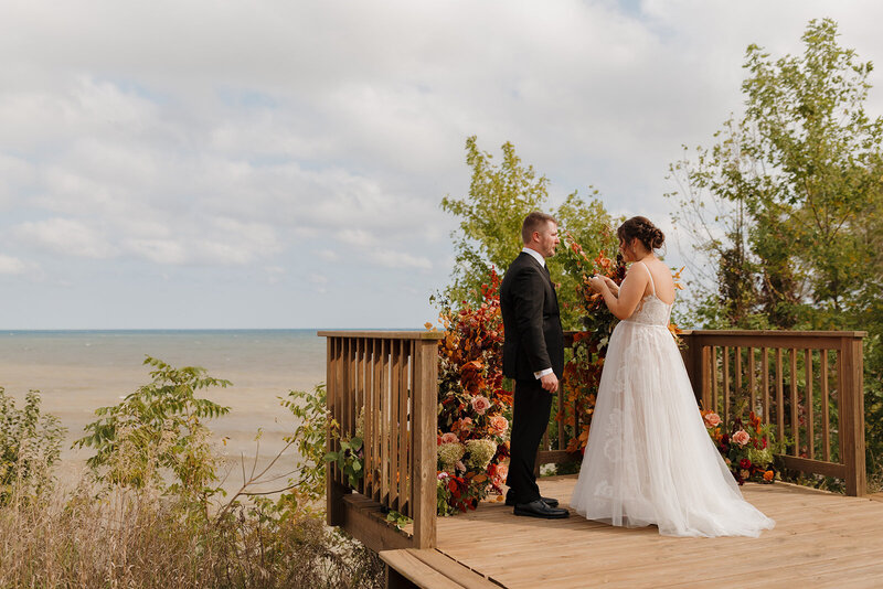 bride and groom exchange private vows after their first look on their wedding day over looking Lake Michigan in sheboygan, wisconsin 