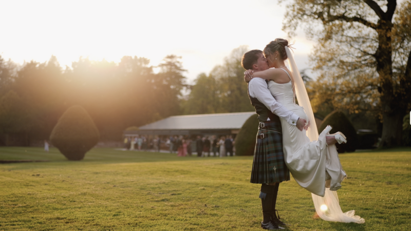 Groom lifting bride in his arms with the Kinmount House Pavillion in the background during golden hour.