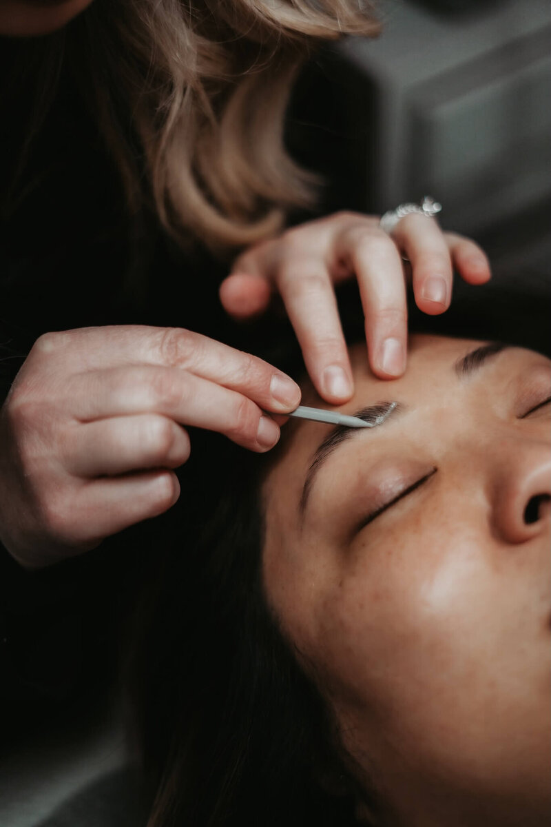 brow technician applying products to her client's brows to laminate them.
