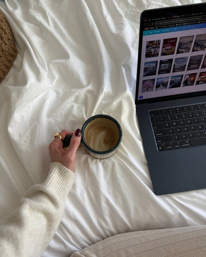 content creator assistant sitting on her bed holding coffee with her laptop