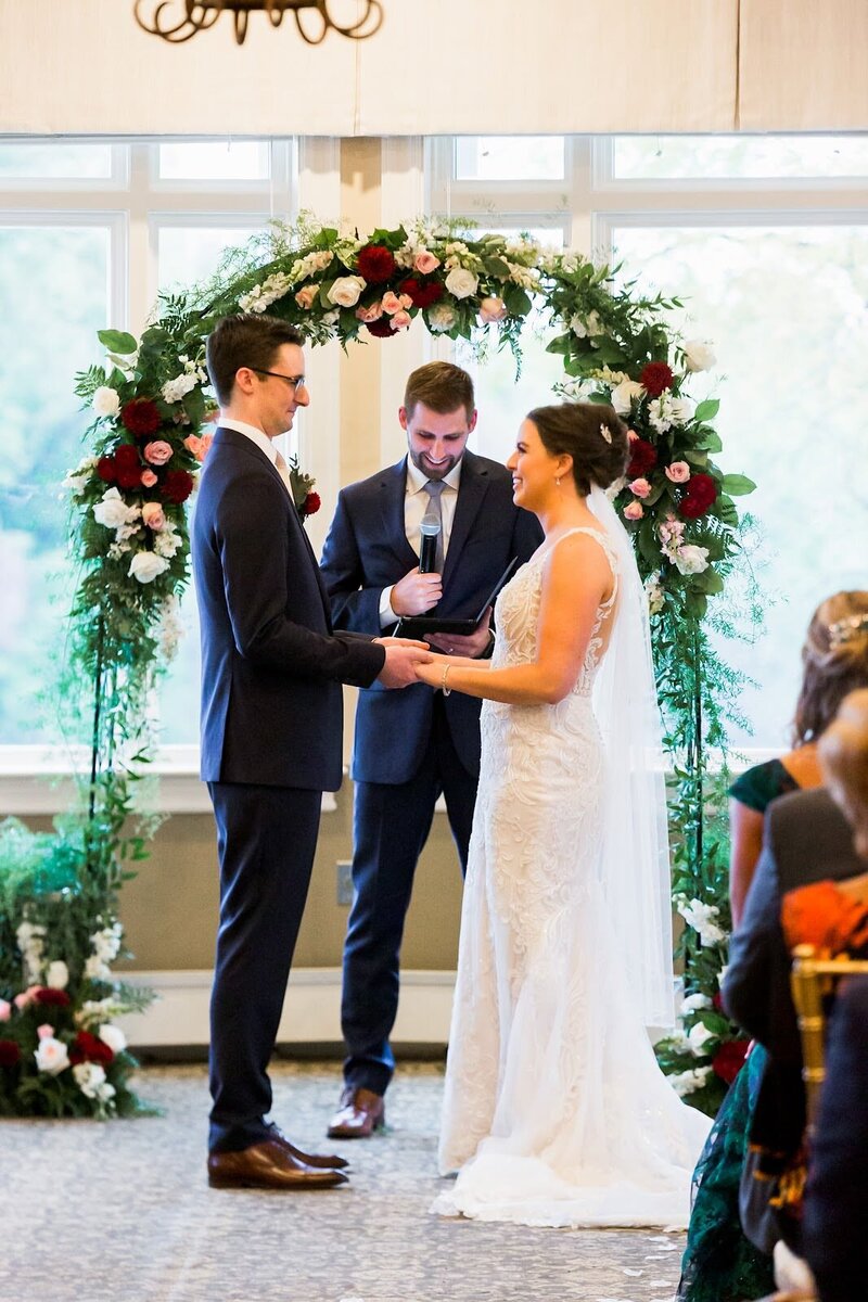 Bride and groom laugh while holding hands during their wedding ceremony