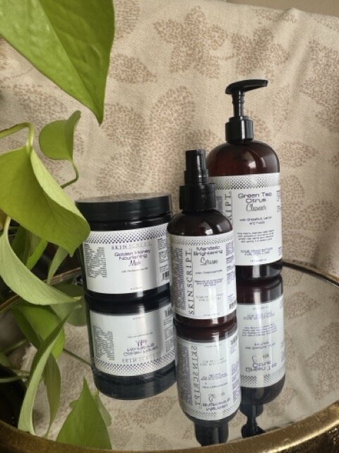 The skin products sit on a table next to a plant, representing products used during facials with Libby in her Eugene studio. 