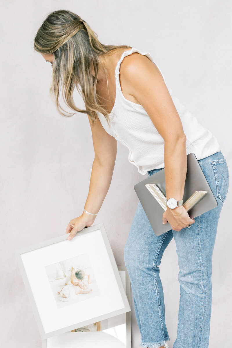 Photographer holding a framed print and laptop, preparing for a personalized design appointment