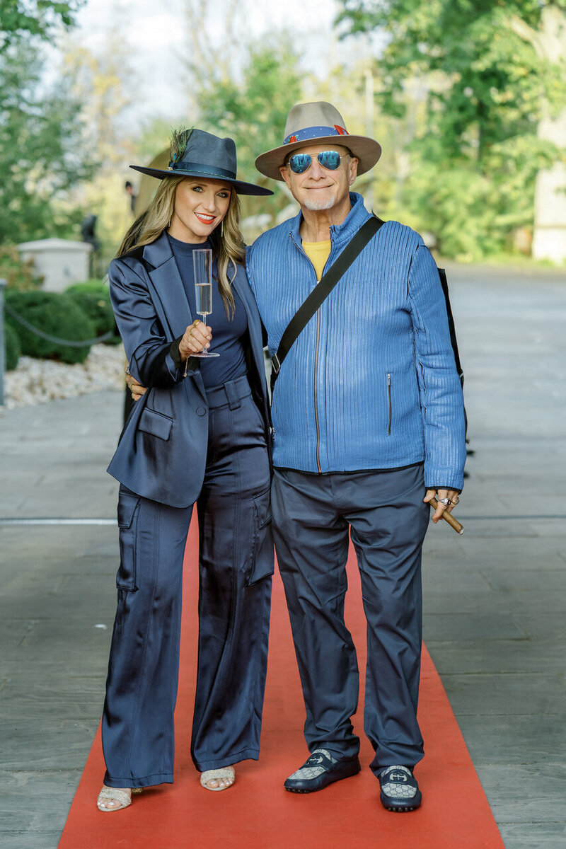 Two people dressed in coordinated blue outfits and hats posing outdoors.