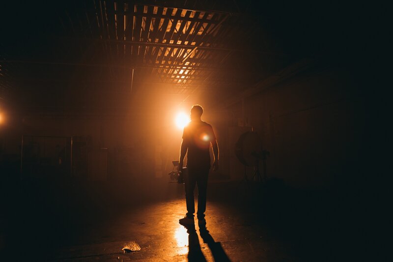 Cinematic behind-the-scenes image of videographer in moody lighting during professional video shoot