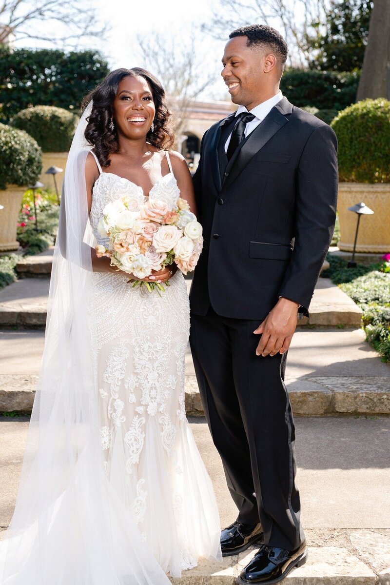  Bride holds her bouquet and poses with her husband at her wedding