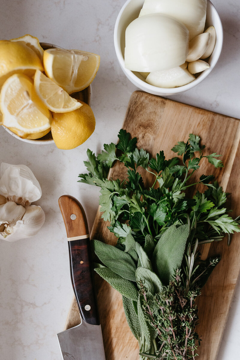 A flat lay of fresh herbs, garlic, lemons, and a knife, symbolizing the wholesome and natural approach to nutrition for both humans and pets.