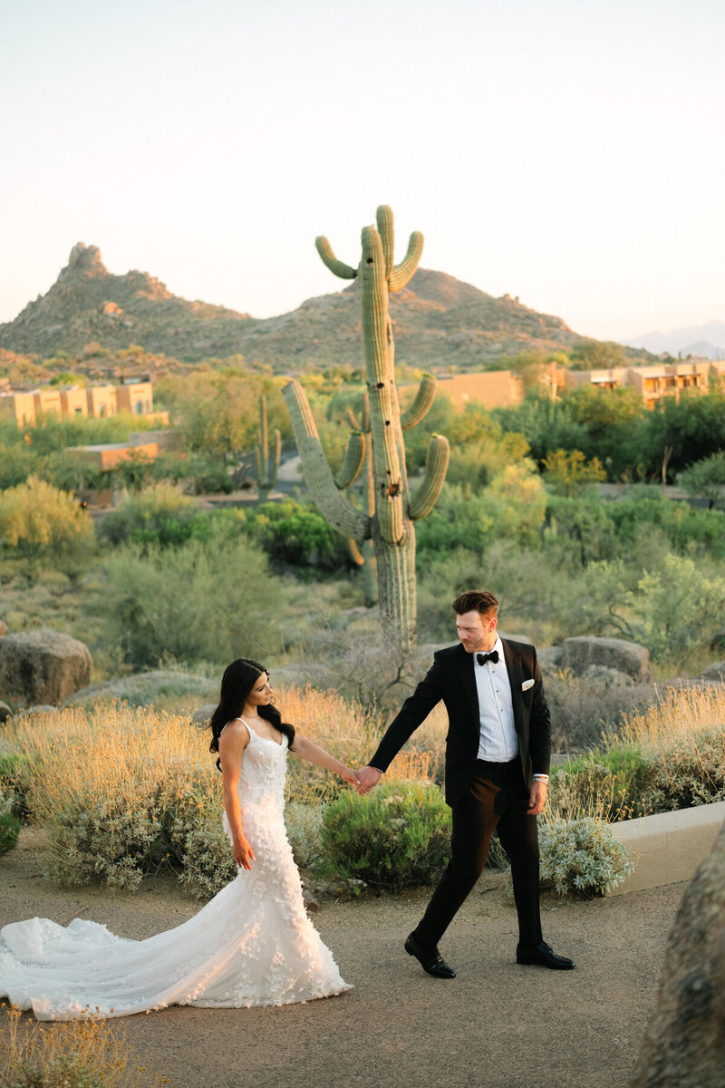 Bride and groom holding hands walking at sunset at the Four Seasons in Arizona