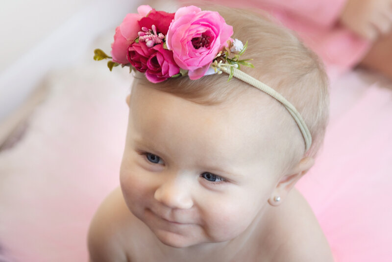 first birthday for little girl with flower headband and pink background