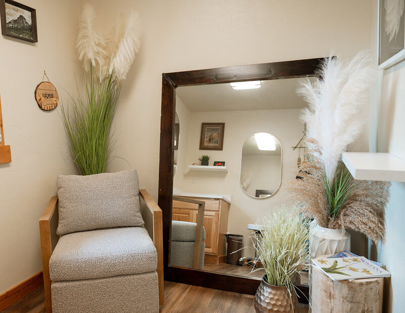 A photo showing the warm and inviting denture clinic waiting area, decorated in neutral colors and faux potted plants in tall vases.