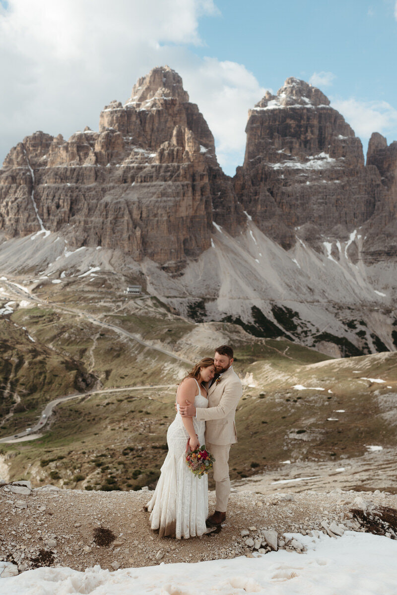 Couple shares a tender embrace with Tre Cime in the background of their Dolomites elopement