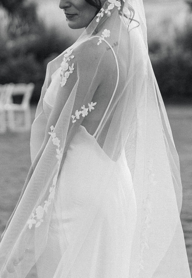 Black and white wedding photo of a bride's dress covered by her veil with lace at The Venue at Willow Creek Farms in Larkspur
